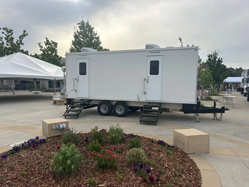 Restroom trailer next to an event tent at an outdoor venue