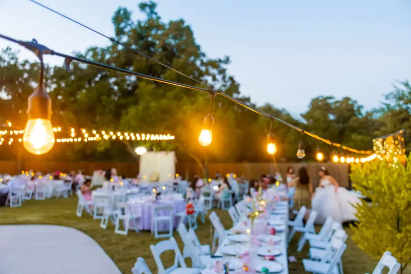 Outdoor wedding reception tables under string lights at dusk