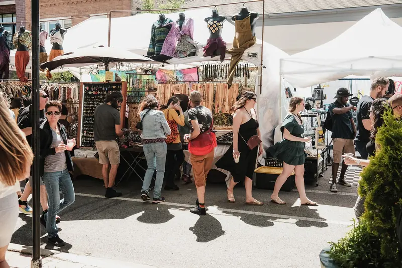 Shoppers browsing vendor booths at a neighborhood street fair